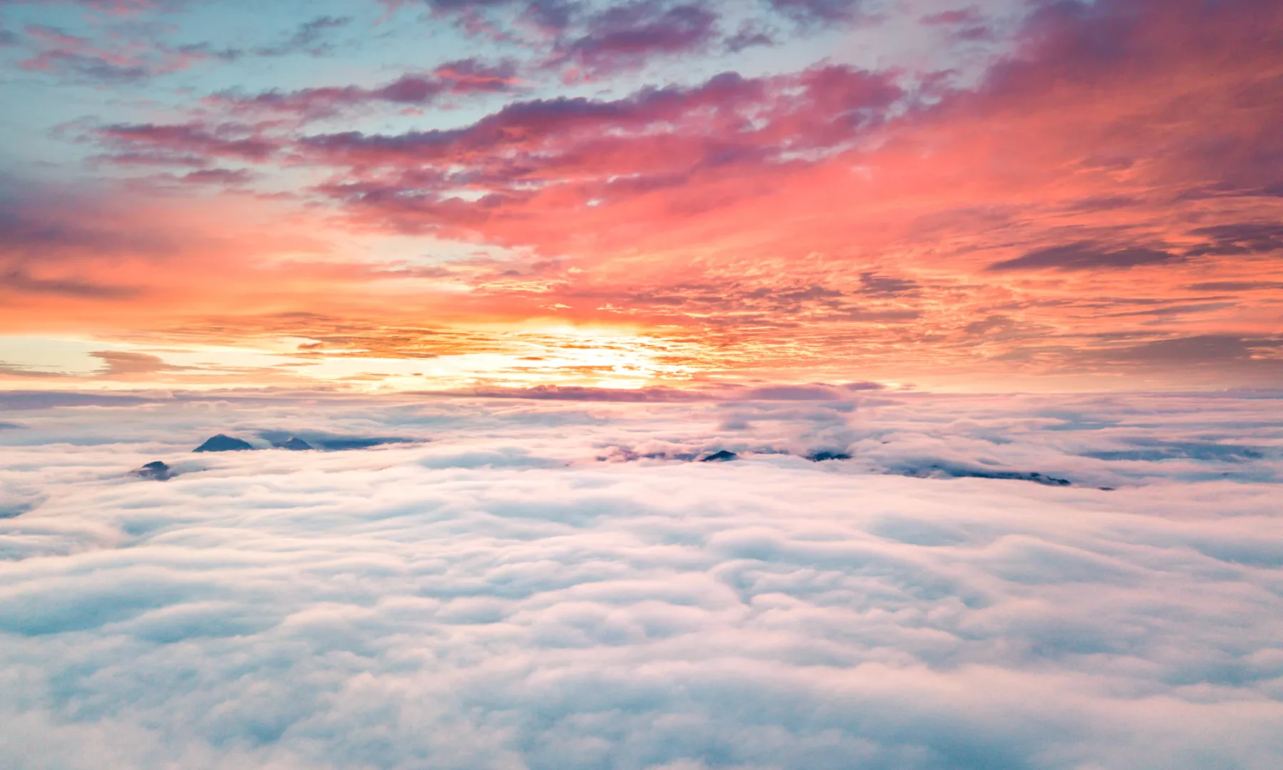 Sunset over a sea of clouds, seen from a plane window
